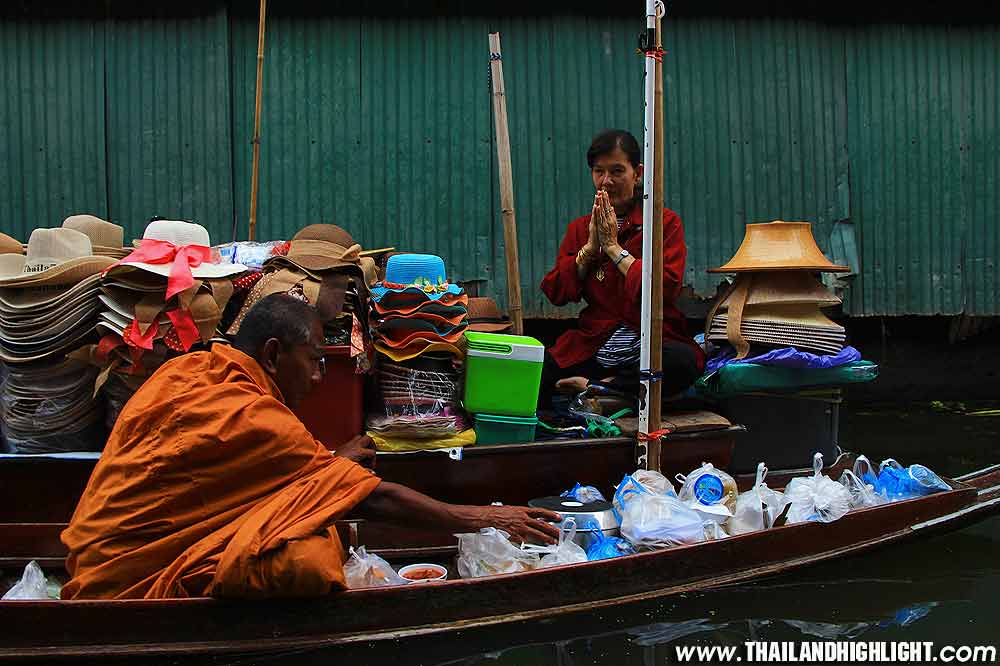Local Thai people make merit to offer food to the monks or  to give alms to the monks at floating market damnoen saduak, travel to the one best famous floating market 